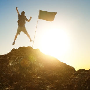 graphicstock-success-leadership-achievement-and-people-concept-silhouette-of-young-guy-with-flag-on-mountain-top-over-sky-and-sun-light-background_HOb5ehvxil